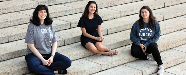 Three women sit side-by-side on stone steps